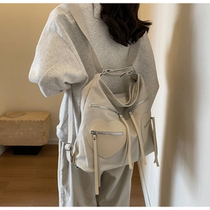 Detail of large beige corduroy backpack showing unique heart-shaped side pockets with zippers