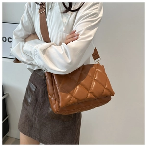 Borsa a tracolla trapuntata marrone con ampia tracolla indossata da una modella