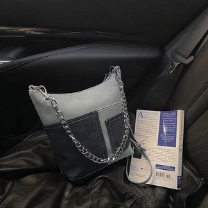Patchwork denim bucket bag with silver chain strap placed on leather car seat
