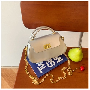 Close-up of silver leather handbag with gold metal lock and chain on book background