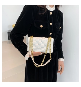 Detail of white heart-quilted handbag with premium gold chain strap on velvet dress