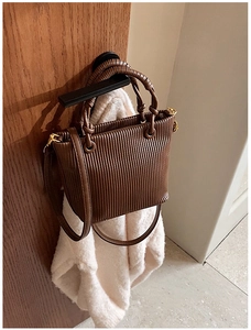 Detailed close-up of dark brown pleated bucket bag with vertical ridges and gold metal hardware