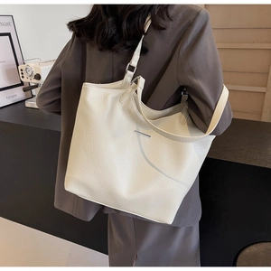 Detail of large cream tote bag with lychee texture leather and metal decor on shoulder