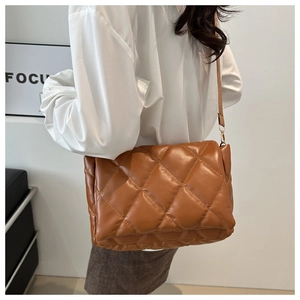 Borsa a tracolla trapuntata marrone con dettagli dorati mostrata su modella con stile