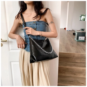 Detail view of black glossy tote bag with chunky silver chain and thin shoulder strap