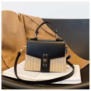 Detailansicht der Strohhandtasche mit schwarzer Lederklappe und goldenem Verschluss