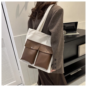 Detail of canvas tote bag showing two brown PU leather front pockets and silver snap buttons