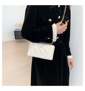 Detail of white quilted leather texture and elegant gold metal chain strap on handbag