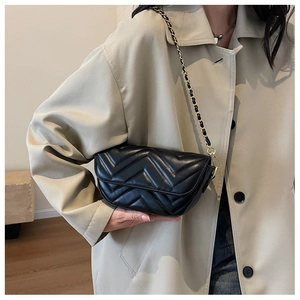 Detailed close-up of a black quilted leather shoulder bag with gold chain strap