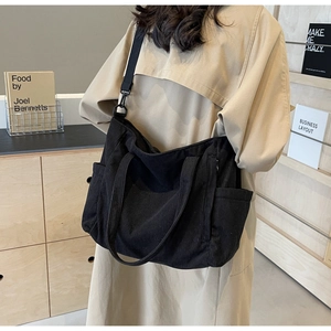 Detail view of black corduroy tote bag featuring side pockets and adjustable shoulder strap