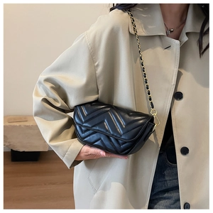 Detail of black quilted leather shoulder bag featuring V-shaped texture and gold chain strap