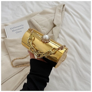 Detail of gold cylinder clutch bag with large pearl clasp and metallic chain handle