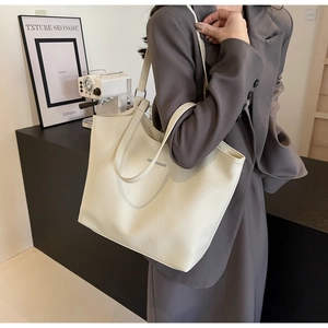 Close-up of cream faux leather tote bag with lychee texture and metallic logo detail