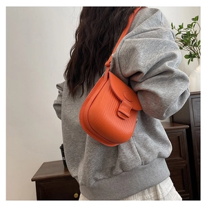 Detail of orange textured crossbody bag with vertical stripe pattern and logo buckle strap
