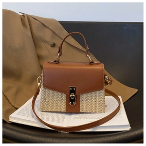 Detailaufnahme der Strohhandtasche mit brauner Lederklappe und goldenem Metallverschluss