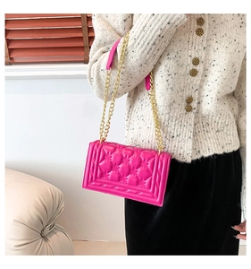 Detailed view of fuchsia quilted chain bag with gold metal strap and leather shoulder pad
