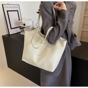 Close-up of creamy white lychee grain leather tote bag with silver metal logo detail
