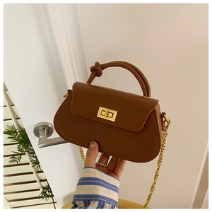 Close-up of brown vintage crossbody bag with knotted handle and gold metal chain strap