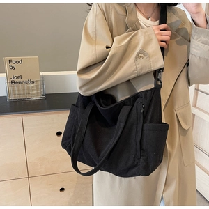 Detailed view of black corduroy tote bag showing striped texture and adjustable strap