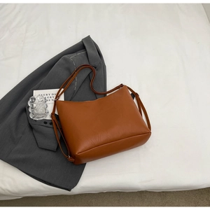 Minimalist caramel brown tote bag detail showing fine texture and sleek shoulder strap