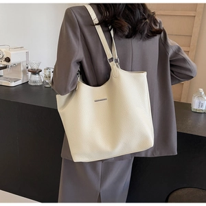 Detail of soft cream lychee grain leather tote bag with metal trim on coffee shop background