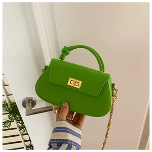 Close-up of bright green PU leather handbag with golden metal lock and chain strap