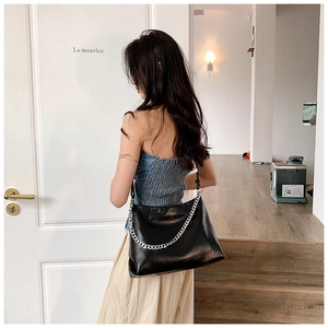 Detail of the black leather shoulder bag showing the silver chain and adjustable strap