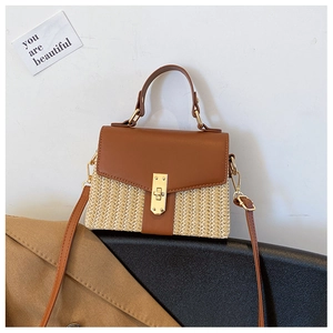 Detailansicht des Strohgeflechts mit goldenem Metallverschluss an brauner Handtasche