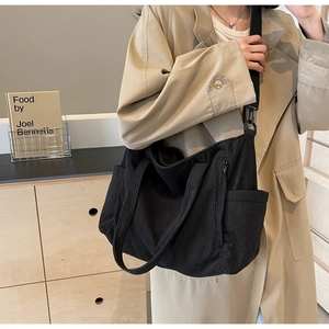 Close-up of black corduroy tote bag featuring adjustable shoulder strap and side pocket detail