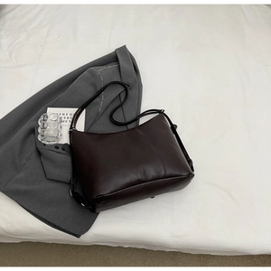 Top view of a dark brown vintage faux leather tote bag on white fabric for daily commute
