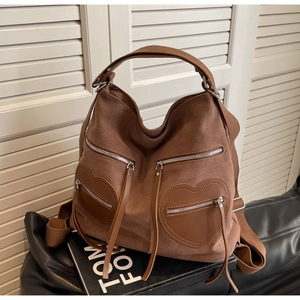 Detail of caramel corduroy hobo bag featuring twin heart-shaped leather pockets