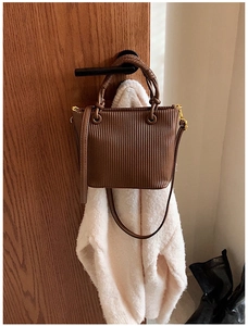 Detailed view of dark brown pleated texture on a vintage style shoulder bucket bag