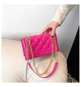 Close-up of fuchsia quilted handbag with gold chain strap and luxury leather texture