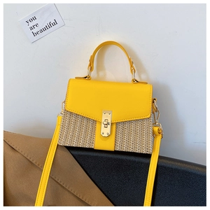 Detail der gelben PU-Klappe und Strohkörper mit goldenem Drehverschluss am kleinen Tasche