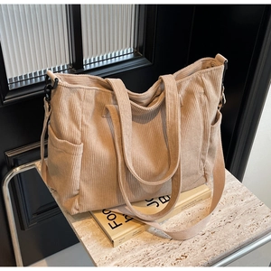 Detail view of corduroy tote bag with side pocket and adjustable strap on marble surface