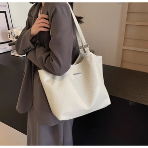 Detailed close-up of cream leather tote bag featuring fine litchi grain and silver hardware