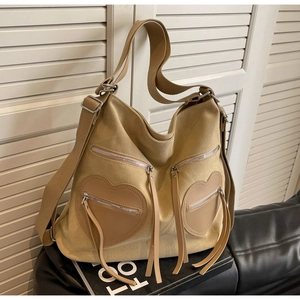 Detail view of khaki corduroy backpack with heart-shaped zipper pockets and wide straps