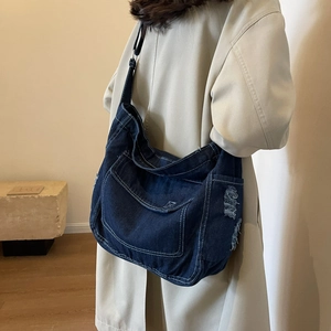 Borsa hobo in denim blu scuro con cuciture bianche e dettagli usurati su una modella