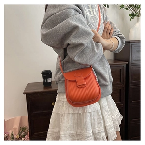 Detail of orange textured leather crossbody bag with vertical embossing and fashion engraving