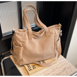 Macro detail of beige corduroy tote bag showing textured fabric and reinforced handles