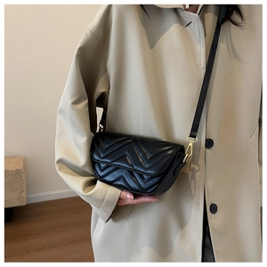 Close-up of black chevron quilted crossbody bag with golden metal hardware detail