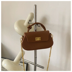 Detail of dark brown leather crossbody bag with elegant gold twist lock and chain strap