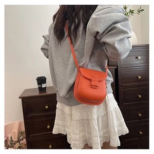 Detail of orange leather crossbody bag with vertical textures shown on model