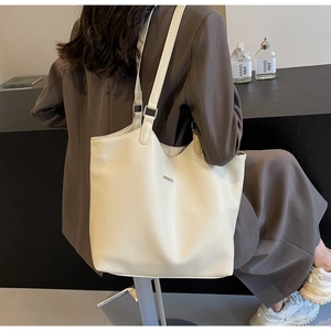Detail shot of a minimalist beige tote bag in litchi grain faux leather for daily commuting