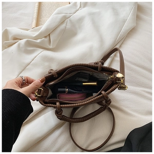Macro shot of dark brown woven handle and gold zipper closure on the bucket bag