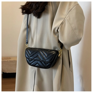 Detail of black chevron quilted leather crossbody bag with elegant gold metal hardware