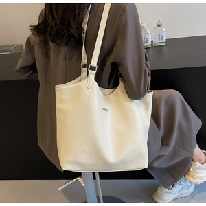 Detailed view of cream textured leather tote bag with silver metal strap hardware and buckle