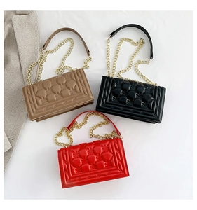 Flat lay of quilted leather flap bags in brown, black and red with gold chain straps
