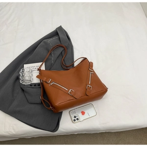 Detail view of large brown leather tote bag with silver zippers and adjustable strap