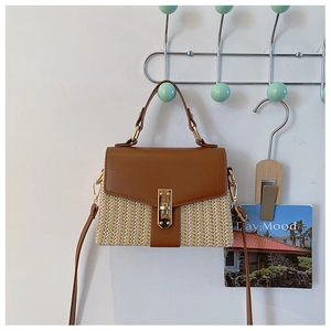 Detail der gewebten Stroh- und Lederhandtasche mit Goldschnalle vor weißer Wand
